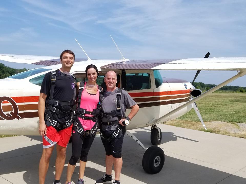 Three people standing outside an airplane